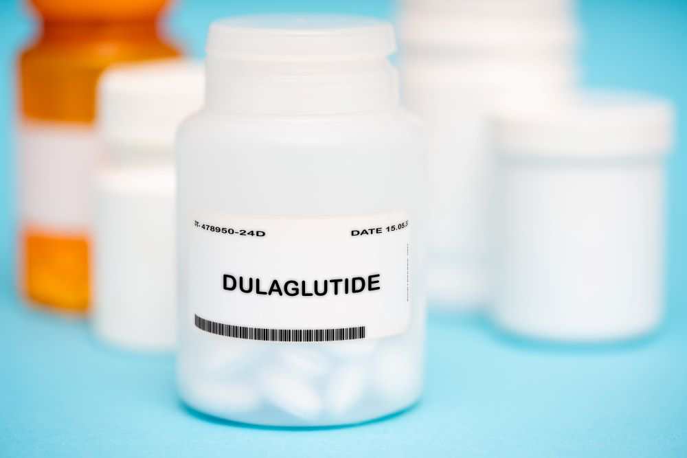 White label oral GLP-1 peptide Dulaglutide capsules bottle on blue background with blurred medicine containers