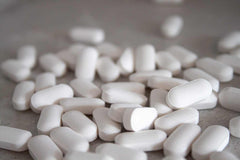 White caplets of Naproxen Sodium or Ibuprofen combined with Omeprazole for anti-inflammatory and stomach protection
